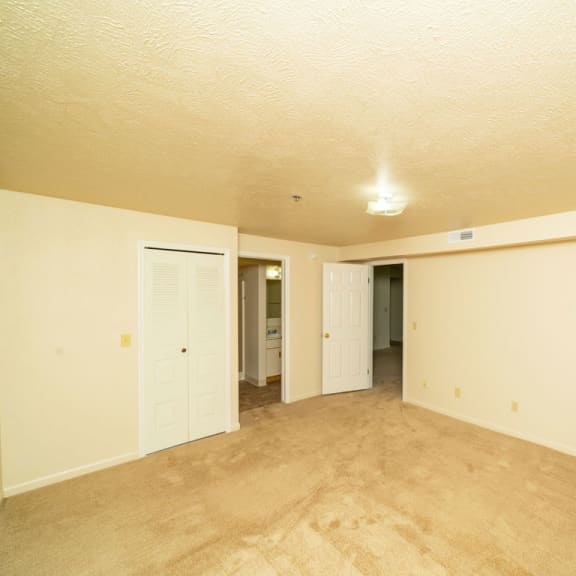 Thumbnail 11 of 12 the living room and dining room of an empty home with white walls and carpet at Trillium Pointe Apartment Homes, Michigan, 49201