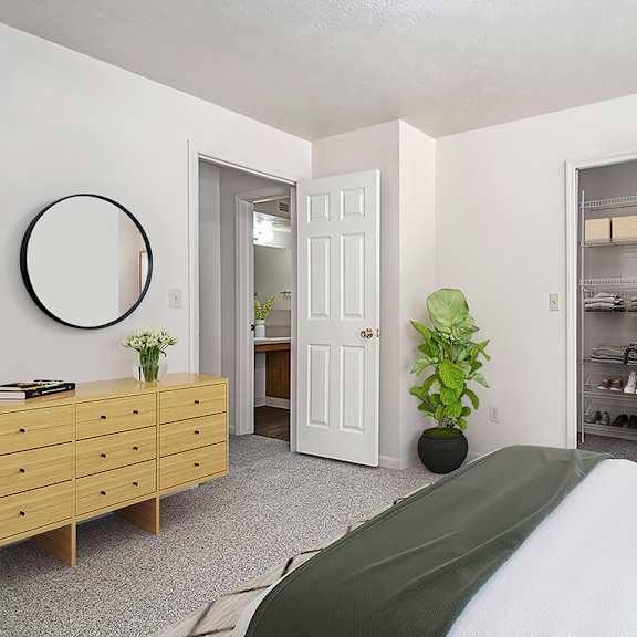 Thumbnail 7 of 7 A bedroom with a bed, dresser, and a walk-in closet with wardrobe organizers at Trillium Pointe Apartment Homes, Jackson