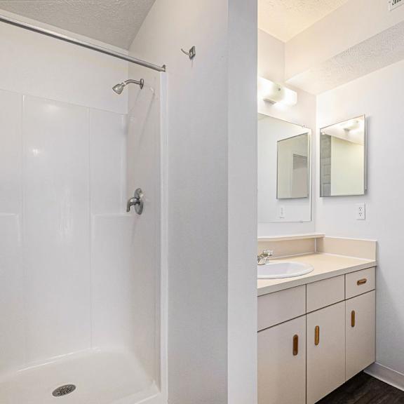Thumbnail 19 of 19 A white bathroom with a shower, toilet, and sink at Trillium Pointe Apartment Homes, Michigan, 49201