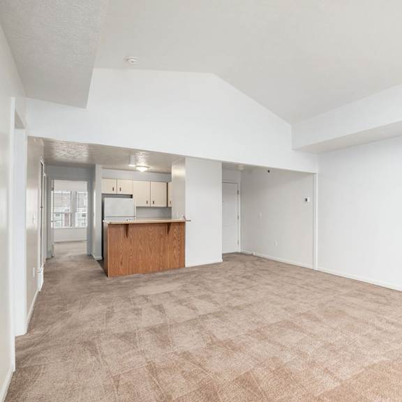 Thumbnail 7 of 19 A large empty dining room with a kitchen area in the background at Trillium Pointe Apartment Homes, Michigan, 49201