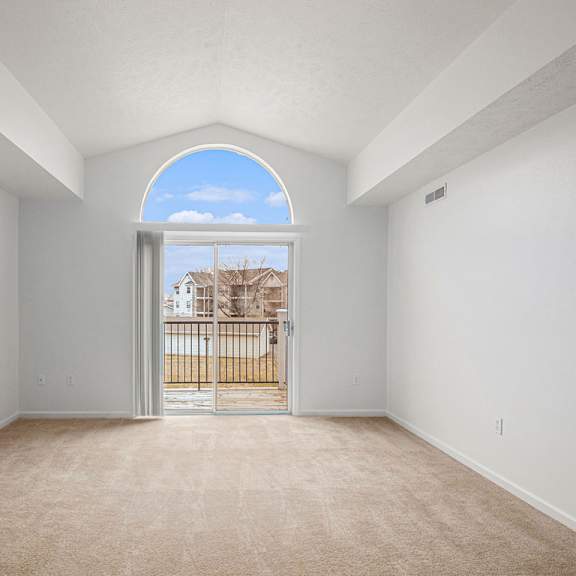 Thumbnail 3 of 19 A spacious living room with a cathedral ceiling and a view of a balcony at Trillium Pointe Apartment Homes, Michigan, 49201