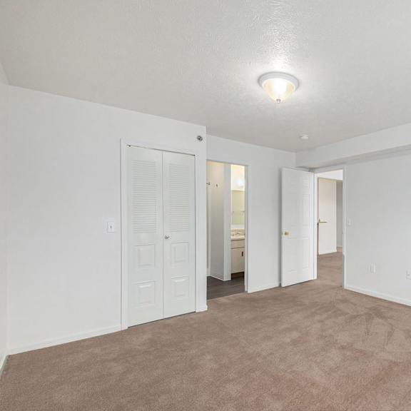 Thumbnail 16 of 19 A large, empty bedroom with an ensuite and walk-in closet at Trillium Pointe Apartment Homes, Michigan, 49201