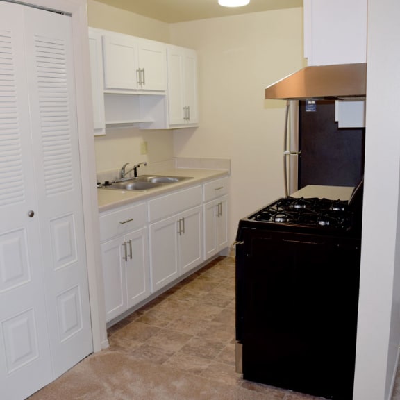 Thumbnail 4 of 7 a kitchen with white cabinets and a stove and a sink at Walnut Trail Apartments, Portage