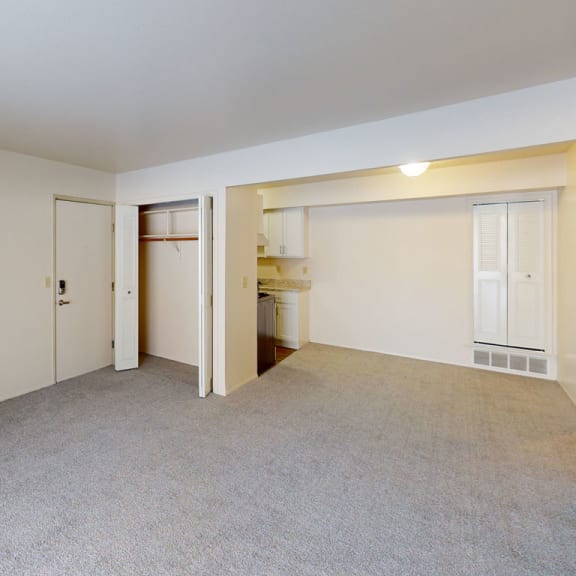 Thumbnail 4 of 8 an empty living room with a door to a bathroom and a closet at Walnut Trail Apartments, Michigan