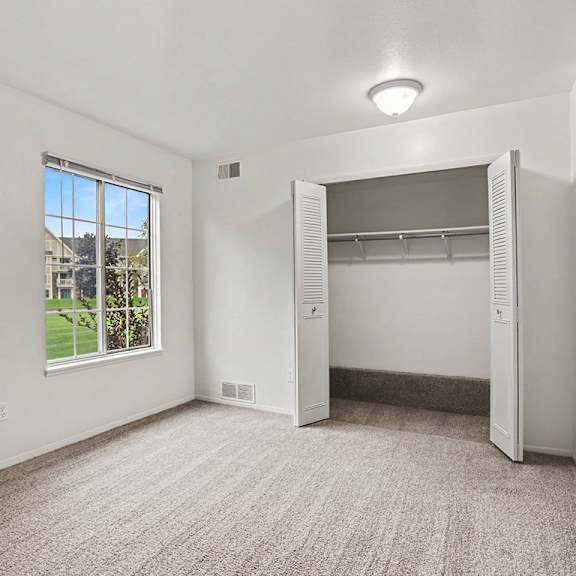Thumbnail 10 of 11 A spacious bedroom with a large window and a closet at Walnut Trail Apartments, Michigan