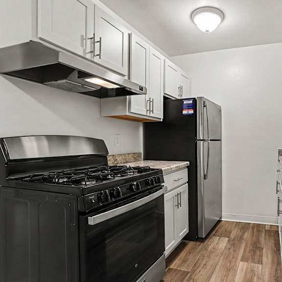 Thumbnail 7 of 11 An upgraded kitchen with stainless steel appliances and white cabinets at Walnut Trail Apartments, Michigan