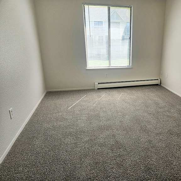Thumbnail 15 of 16 A bedroom with a window and plush carpet at Waverly Park Apartments, Lansing