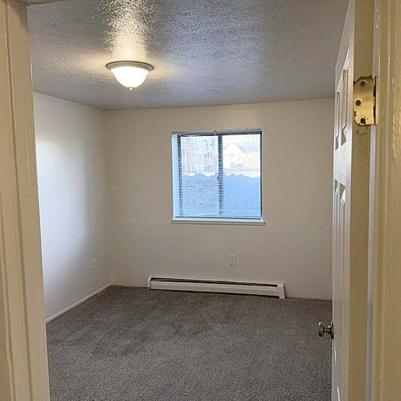 Thumbnail 11 of 11 A bedroom with a window and plush carpet at Waverly Park Apartments, Lansing