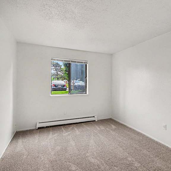Thumbnail 11 of 12 A bedroom with a window and a carpeted floor at Waverly Park Apartments, Lansing, Michigan