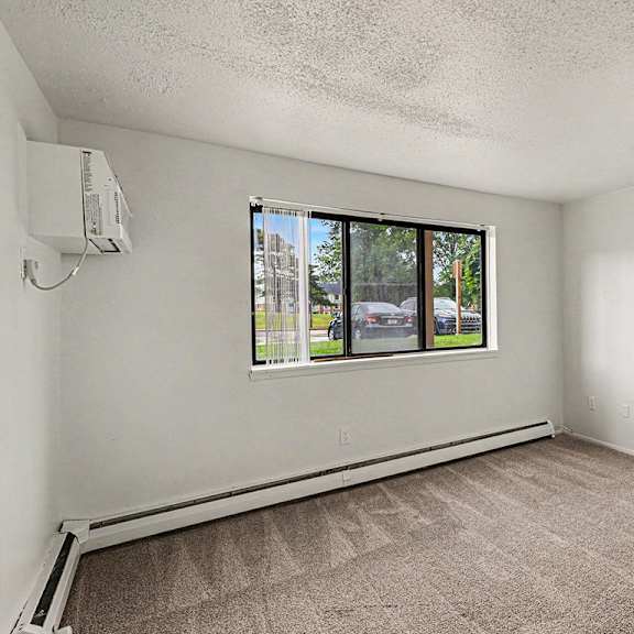 Thumbnail 3 of 12 A living room with a window and a carpeted floor at Waverly Park Apartments, Lansing, Michigan