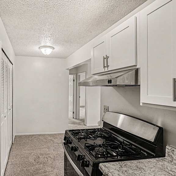 Thumbnail 8 of 15 A kitchen with a stainless steel stove top oven and white shaker cabinets at Waverly Park Apartments, Lansing, Michigan