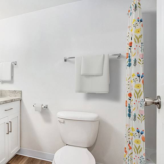 Thumbnail 13 of 17 A bathroom with a toilet next to a sink and large vanity with mirror at West Hampton Park Apartments in Elkhorn, NE 68022