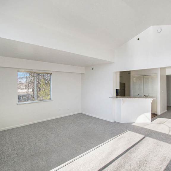 Thumbnail 5 of 12 A spacious living room with a grey carpet and cathedral ceiling at West Hampton Park Apartments in Elkhorn, NE 68022