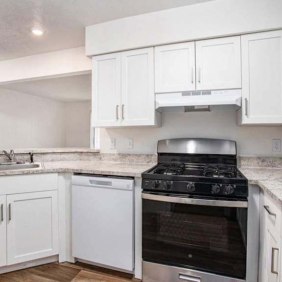 Thumbnail 7 of 14 A kitchen with a gas stove, dishwasher, and white cabinets at West Hampton Park Apartments in Elkhorn, NE 68022