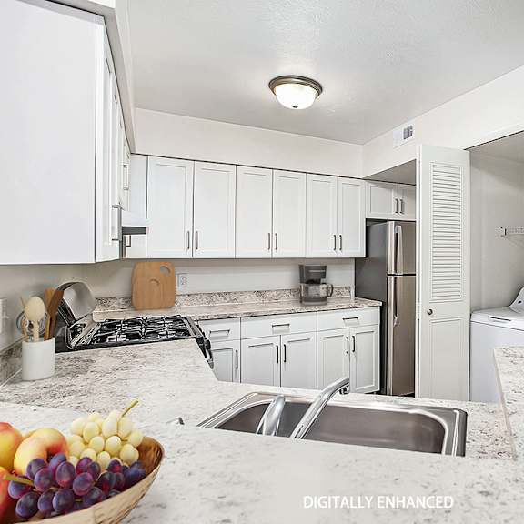 Thumbnail 9 of 14 A kitchen with white cabinets and a full size washer and dryer at West Hampton Park Apartments in Elkhorn, NE 68022