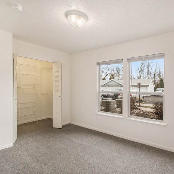 Thumbnail 13 of 20 A bedroom with carpet, a walk in closet door, and a large window at West Hampton Park Apartments in Elkhorn, NE 68022