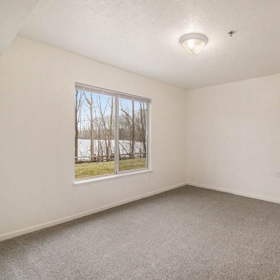 Thumbnail 17 of 20 A bedroom with a large window and a carpeted floor at West Hampton Park Apartments in Elkhorn, NE 68022
