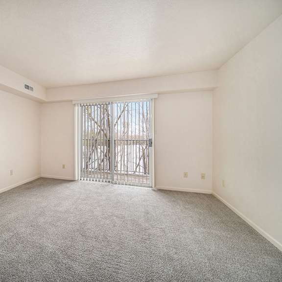Thumbnail 4 of 20 A living room with a carpeted floor and a slider to a balcony at West Hampton Park Apartments in Elkhorn, NE 68022