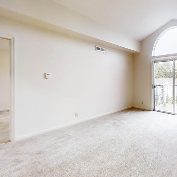 Thumbnail 6 of 20 A spacious living room with a large arched window and carpeted floor at West Hampton Park Apartment Homes, Elkhorn, Nebraska 68022