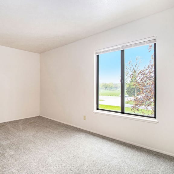 Thumbnail 12 of 13 A spacious bedroom with large window and plush carpeting at Wingate Apartments, Kentwood