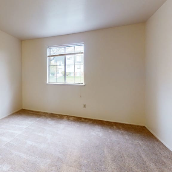 Thumbnail 8 of 8 A spacious bedroom with a window and plush carpeting at Wood Creek Apartments, Kenosha, Wisconsin