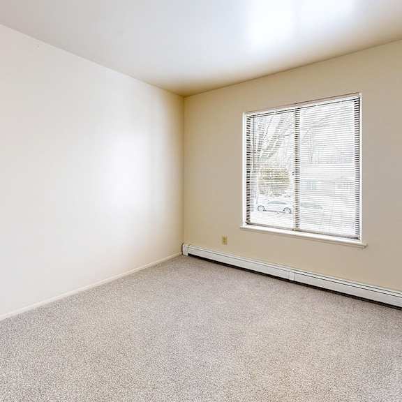 Thumbnail 8 of 8 A spacious bedroom with a window and plush carpeting at Wood Creek Apartments, Kenosha, WI, 53144