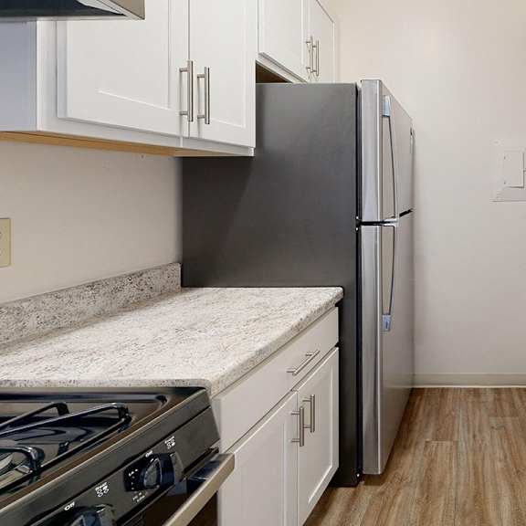 Thumbnail 6 of 8 An upgraded kitchen with white cabinets and stainless steel appliances at Wood Creek Apartments, Kenosha, WI, 53144