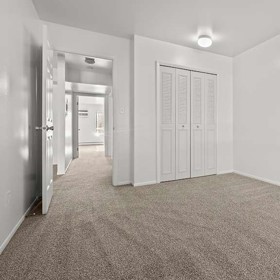 Thumbnail 10 of 14 A bedroom with a carpeted floor and a large closet at Wood Creek Apartments, Kenosha