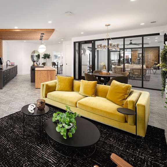 a living room with a yellow couch and a black rug