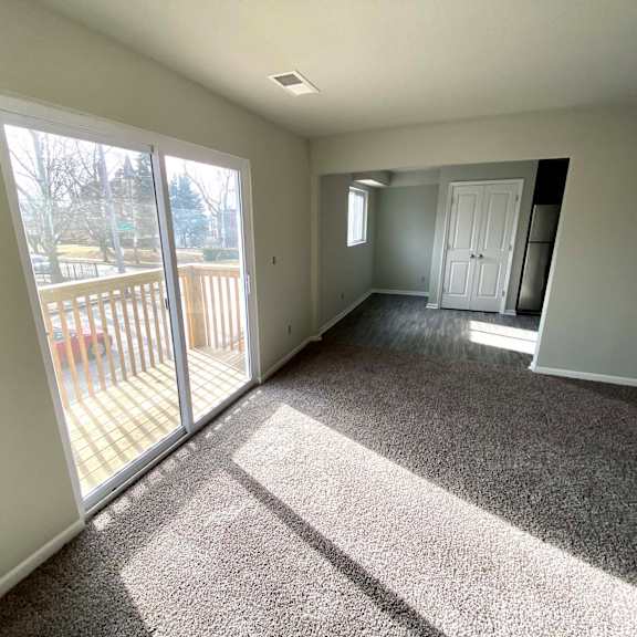 a sunny day with a carpeted room and sliding glass doors.