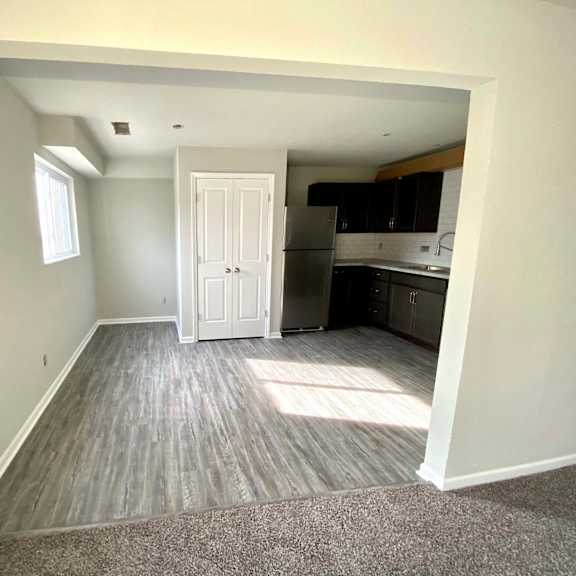 a room with a white door leading to a kitchen.