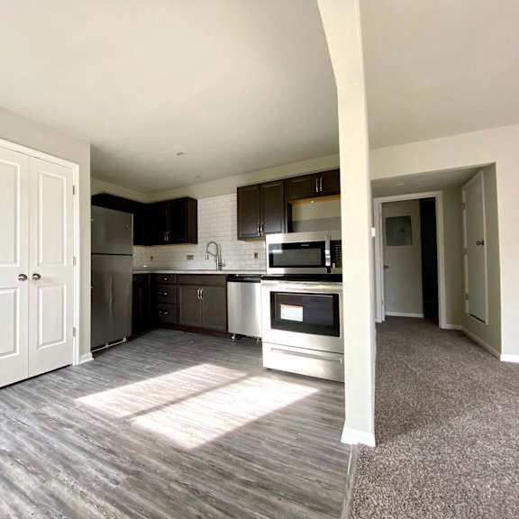 a kitchen with a white door and a microwave above the stove.