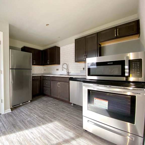 a kitchen with a stainless steel refrigerator, microwave, and oven.