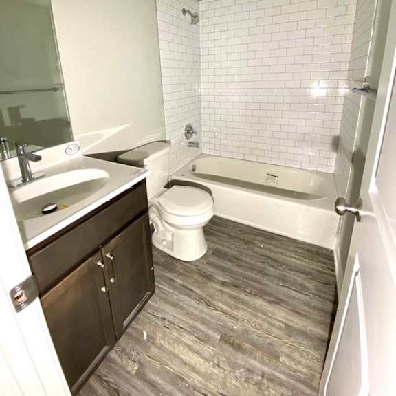 a white tiled bathroom with a wooden floor.