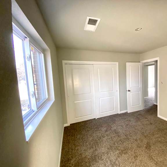 a room with carpeted floor and two doors.