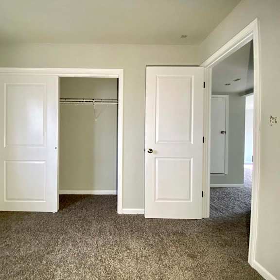 a room with two white doors and carpeted flooring.