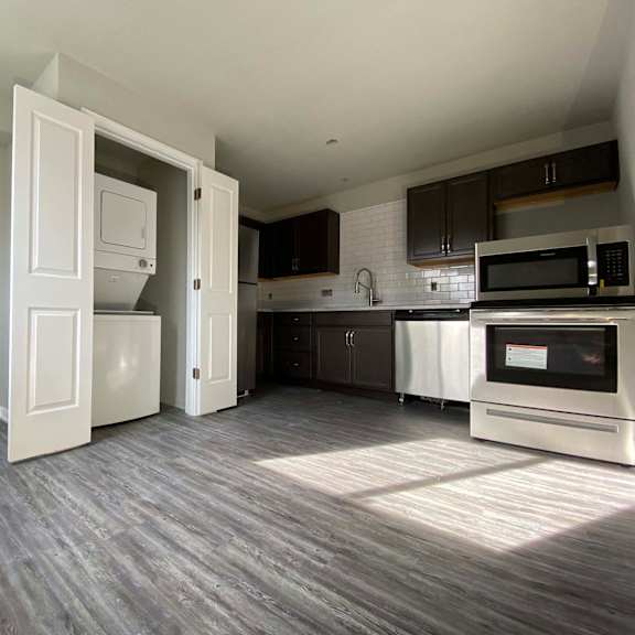 a kitchen with a white fridge and microwave, and a wooden floor.