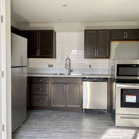 a kitchen with dark brown cabinets and a white tiled backsplash.
