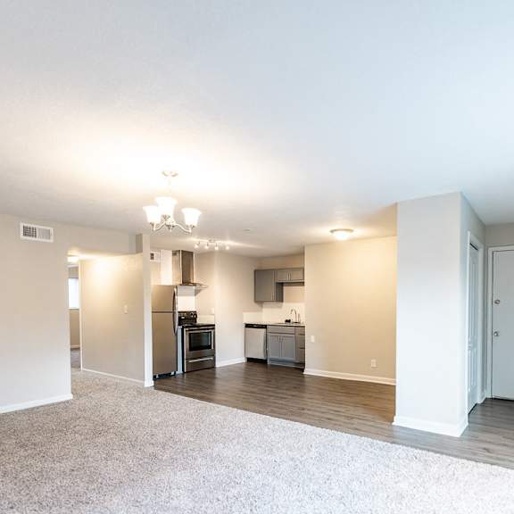 a spacious living room with a kitchen in the background.