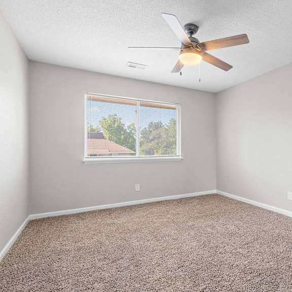 a room with a ceiling fan and carpeted floor.