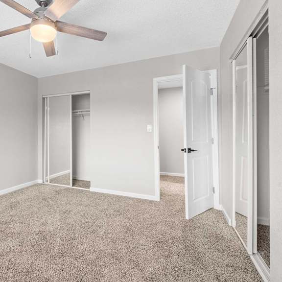 a room with a ceiling fan and carpeted floor.