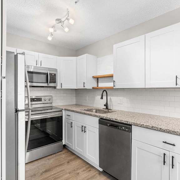 a kitchen with white cabinets and a granite countertop.