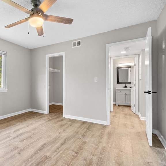 a room with a ceiling fan and a window with trees visible outside.