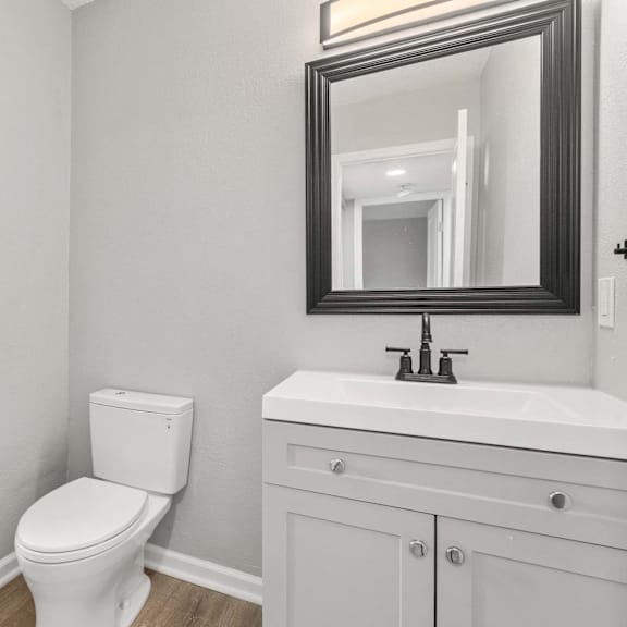 a white bathroom with a toilet, sink, and mirror.