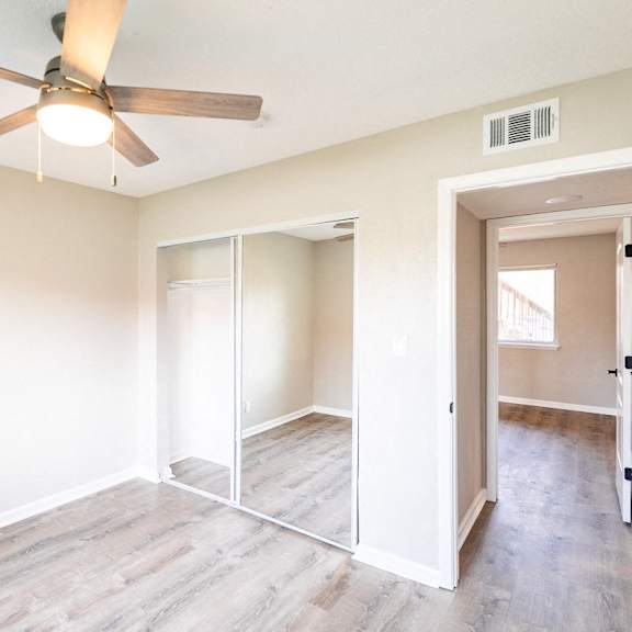 a room with a ceiling fan and sliding doors.