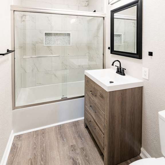 a bathroom with a sink, mirror, and walk-in shower.