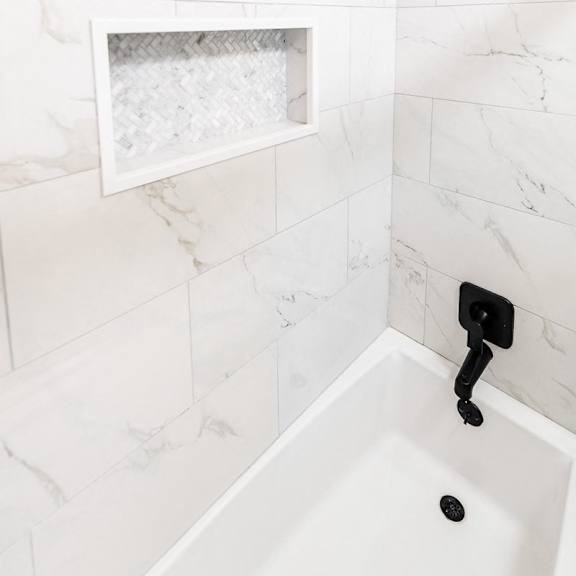 a white bathroom with a marble tile wall and a white sink.