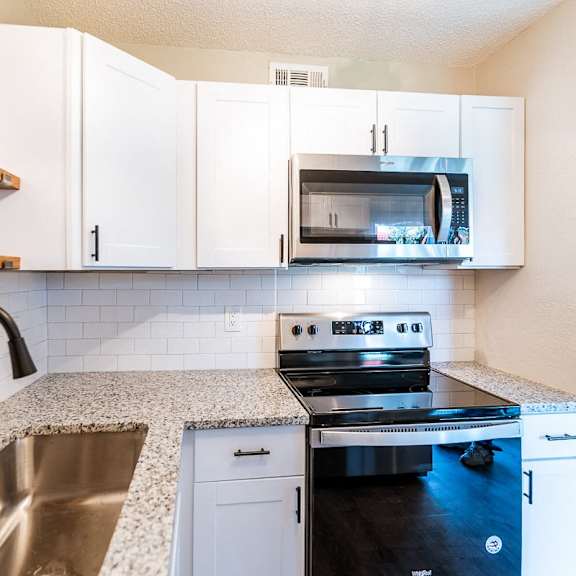 a kitchen with a stove, oven, microwave, and sink.