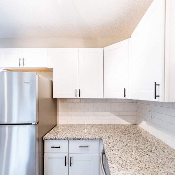 a kitchen with a refrigerator, cabinets, and a washing machine.