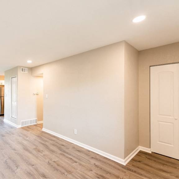 a spacious room with wood flooring and a ceiling fan.